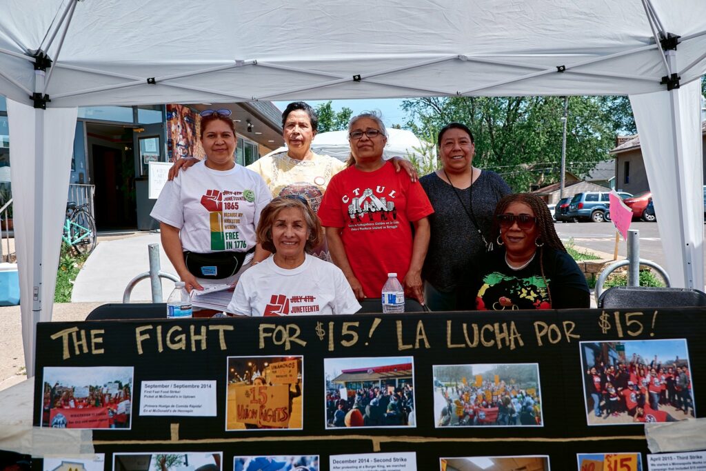 CTUL members and organizers standing behind a poster about the Fight for $15. 