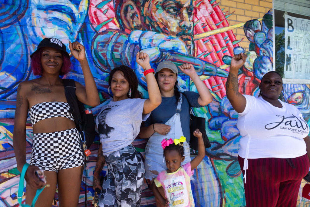 Members and staff from Future Fighters standing with their fists raised in front of a mural.