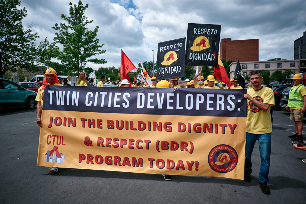 Construction workers leading a march with a banner calling on developers to join the BDR Program.